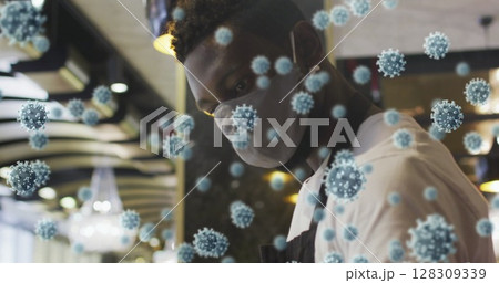 Image of covid-19 cells floating over african american man in face mask disinfecting table Image of covid-19 cells floating over african american man in face mask disinfecting table 128309339