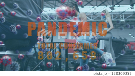 Pandemic text with increasing cases against woman adjusting seat of stationary bike at gym 128309355