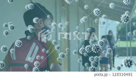 Multiple covid 19 cells floating against school boy wearing face mask standing in a queue at school 128310491