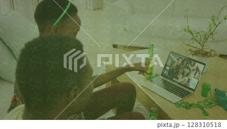 Image of clover over couple celebrating st patrick's day with friends on laptop image call 128310518