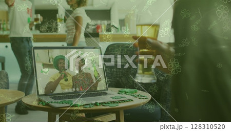 Image of clover leaves over man celebrating st patrick's day with friends on laptop image call 128310520