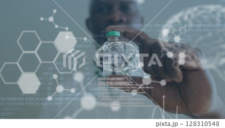 Medical data processing against male doctor wearing face mask holding covid 19 vaccine 128310548