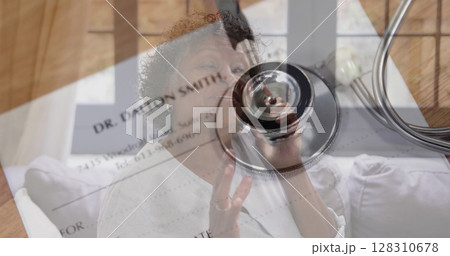 Image of stethoscope and doctor's certificate over senior woman talking on smartphone 128310678