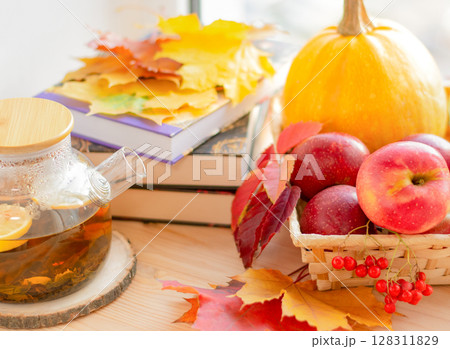 Cozy autumn, books, tea and apples on the windowsill with autumn fallen leaves 128311829