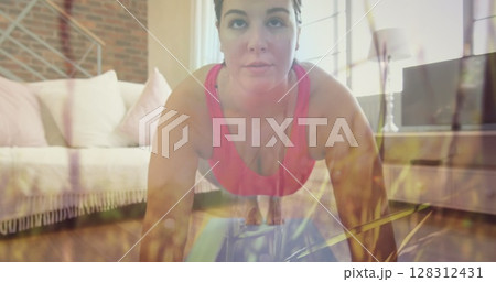 Grass moving in the wind against caucasian woman performing plank exercise at home 128312431