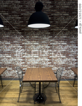 Comfortable library setting with wooden tables and modern chairs against a brick wall Comfortable library setting with wooden tables and modern chairs against a brick wall 128312499
