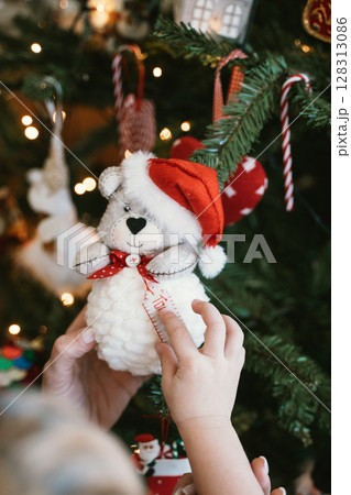 Child Holding Christmas Bear Ornament on Tree 128313086