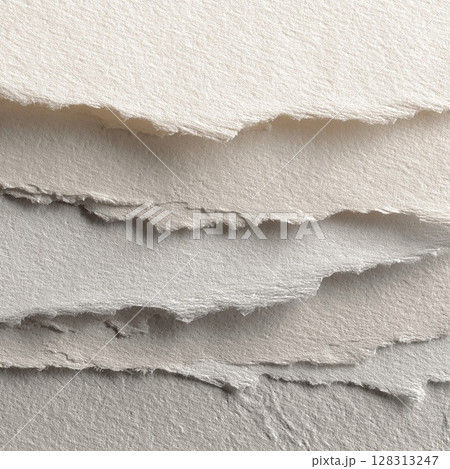 Close-up shot of layered, torn paper edges with a soft, textured appearance. 128313247
