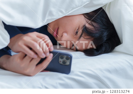 ベッドでスマホを使う男性 128313274
