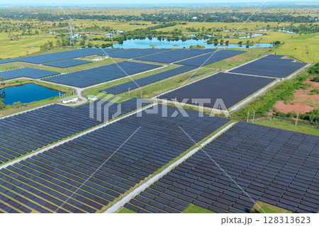 Drone shot aerial view solar energy array provides renewable power in large scale facility surrounded by greenery and water in rural place. Solar farm at the countryside 128313623