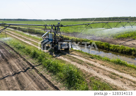 Autonomous machine is moving watering pivot along irrigation canal 128314113