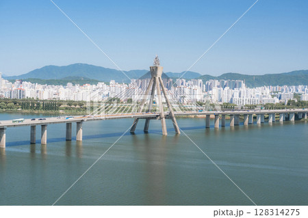 Beautiful view of modern tower and Jamsil Railway Bridge over the Han River (Hangang) at downtown of Seoul in South Korea. Scenic skyscraper is visible on blue sky background. Wonderful cityscape. 128314275