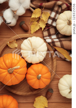 Beautiful mini pumpkins with autumn leaves on brown background. Vertical photo Beautiful mini pumpkins with autumn leaves on brown background. Vertical photo 128315556