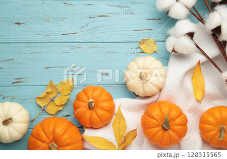 Beautiful mini pumpkins with autumn leaves on blue background Beautiful mini pumpkins with autumn leaves on blue background 128315565