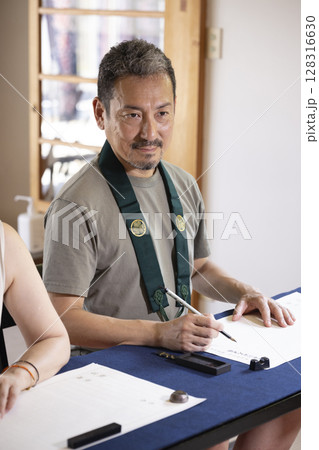 お寺で写経体験をする夫婦 128316630