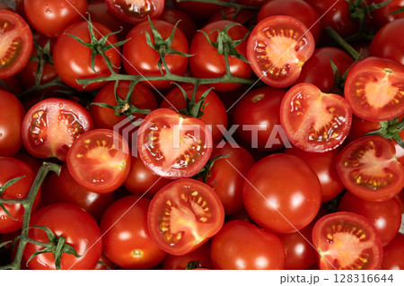 Juicy vegetable tomato background, lots of tomatoes whole and cut in half top view. 128316644