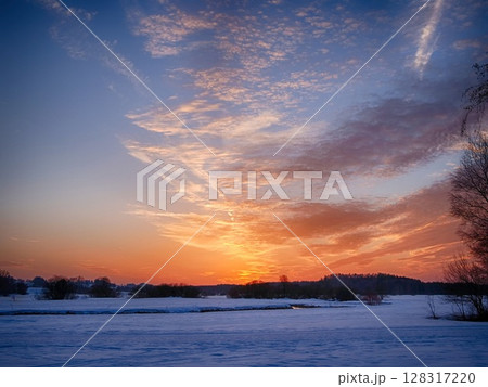 A beautiful sunset over a snow-covered field A beautiful sunset over a snow-covered field 128317220