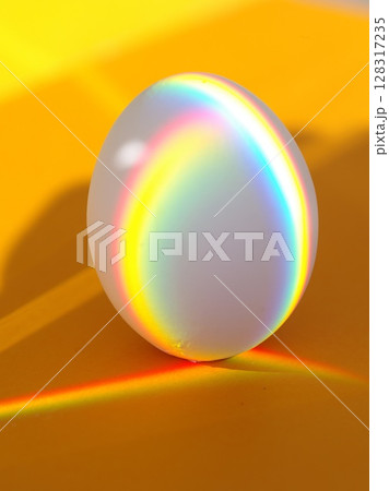 A rainbow egg is sitting on a yellow surface 128317235