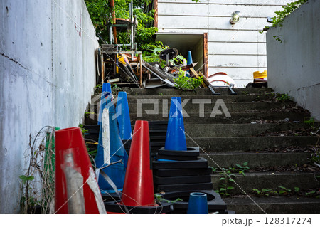 建物の裏の階段にパイロンなどが放置されている 建物の裏の階段にパイロンなどが放置されている 128317274