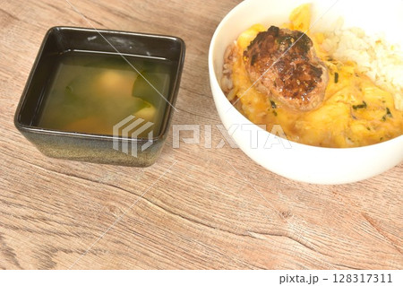 grilled hamburg pork steak and creamy egg omelets topping on rice in bowl with miso or soy sauce soup grilled hamburg pork steak and creamy egg omelets topping on rice in bowl with miso or soy sauce soup 128317311