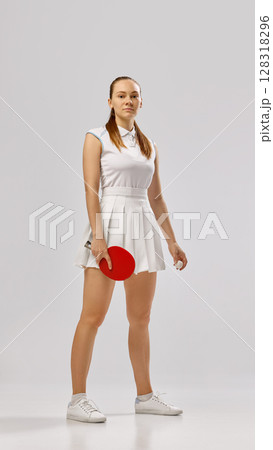 Young woman posing confidently with table tennis paddle 128318296