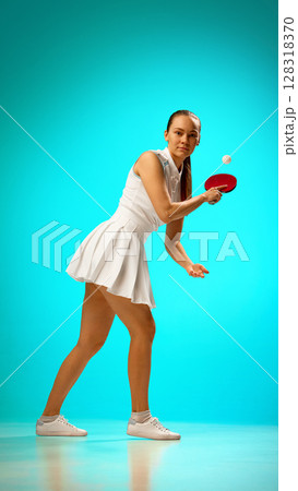 Young woman playing table tennis on vibrant turquoise background 128318370