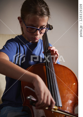 Young Girl Practicing the Cello at Home While Wearing Glasses 128319109