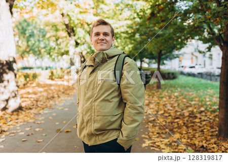 Calm happy 30s Man Relaxing in Autumn Park Outdoors. Traveler. Falling time. Smiling man in casual clothing standing outdoor 128319817