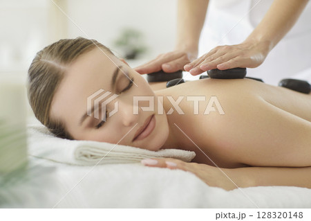 Therapist Performing Stone Massage For Woman In Salon Therapist Performing Stone Massage For Woman In Salon 128320148