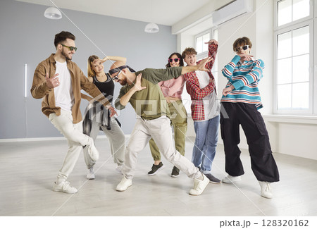 Group of trendy young people dancing in studio, performing hip hop moves and expressing energy. Group of trendy young people dancing in studio, performing hip hop moves and expressing energy. 128320162
