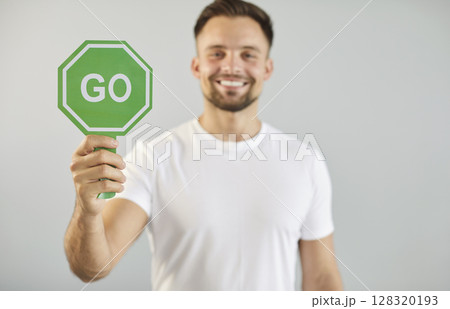 Man holding green sign with Go word to start forward movement, begin challenge or road race 128320193