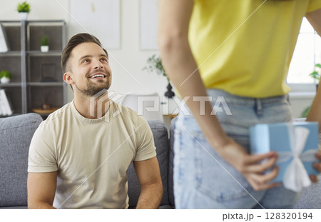 Woman hiding present behind back, congratulating her boyfriend with birthday, preparing surprise 128320194