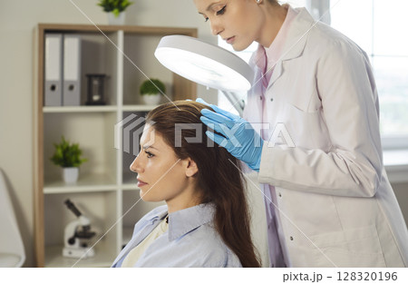 Patient hair and scalp examination by professional trichologist dermatologist with magnifying glass 128320196