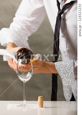 Man waiter pouring wine into glass. 128321233