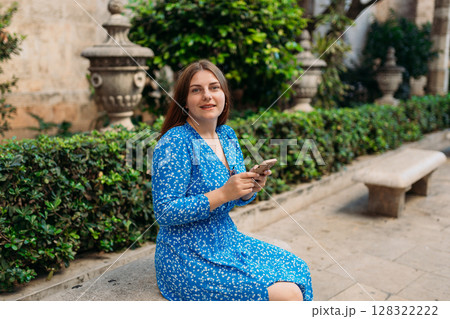 Portrait of happy young woman scrolling information on smartphone in historic city of Spain. Traveling Europe in summer Portrait of happy young woman scrolling information on smartphone in historic city of Spain. Traveling Europe in summer 128322222
