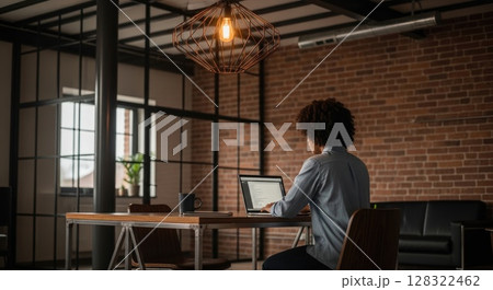 Person working in industrial loft office, back view 128322462