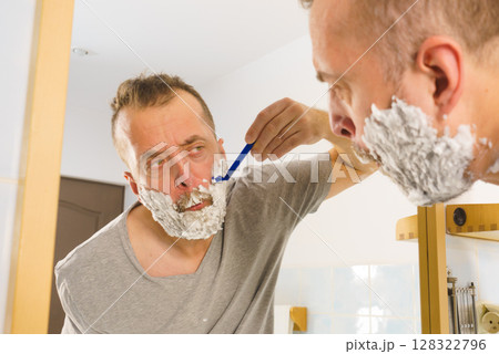 Guy shaving his beard in bathroom Guy shaving his beard in bathroom 128322796