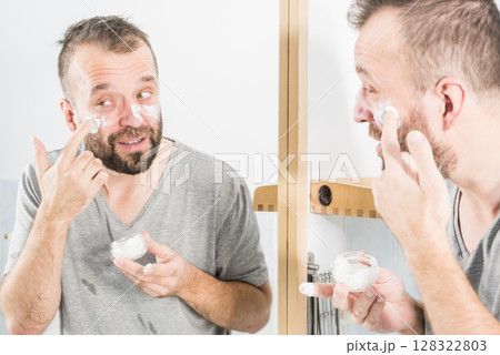 Man applying moisturizer cream in bathroom Man applying moisturizer cream in bathroom 128322803