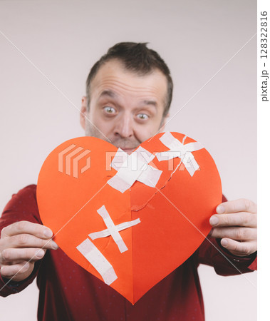 Funny man holds broken heart 128322816