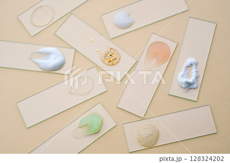 Samples of multi-colored cosmetic products on a beige background. 128324202