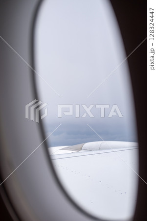 Sky and cloud seen through the window of airplane, with the plane wing 128324447