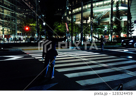 夜の東京国際フォーラム、横断歩道に立つ警備員、誘導員、ガードマン 128324459