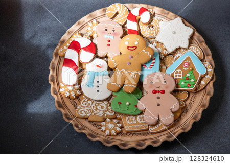 Gingerbread cookies with icing decoration. Christmas food. Gingerbread man baking. Top view table. Xmas sweet on black background Gingerbread cookies with icing decoration. Christmas food. Gingerbread man baking. Top view table. Xmas sweet on black background 128324610