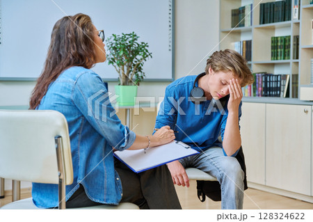 Sad teenage boy in mental therapy session, talking with school counsellor Sad teenage boy in mental therapy session, talking with school counsellor 128324622