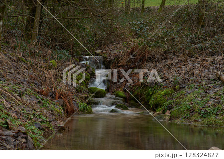 Enchanting Forest Waterfall: Cascading Mountain Stream with Autumn Foliage and Golden Sunset Light. Long Exposure Captures Silky Water Flow Over Moss Covered Rocks in Lush Green Woodland Enchanting Forest Waterfall: Cascading Mountain Stream with Autumn Foliage and Golden Sunset Light. Long Exposure Captures Silky Water Flow Over Moss Covered Rocks in Lush Green Woodland 128324827