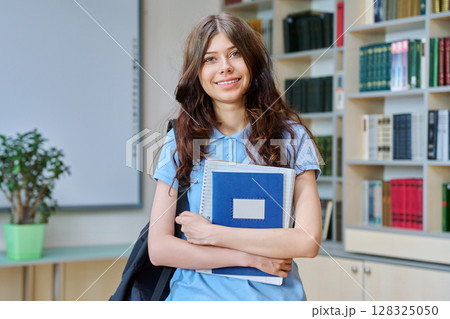 Portrait of teenage beautiful girl high school student posing in library classroom 128325050