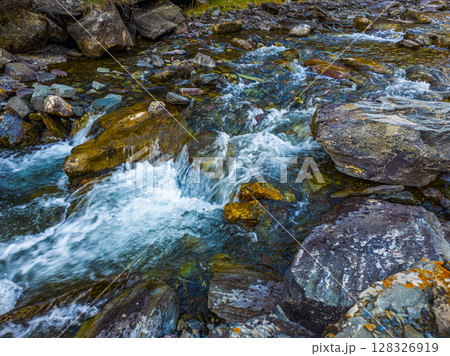 Cascading mountain stream flowing over colorful rocks in Kyrgyzstan Cascading mountain stream flowing over colorful rocks in Kyrgyzstan 128326919