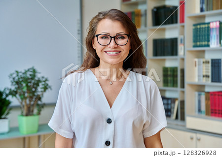 Headshot portrait smiling mature woman teacher in classroom Headshot portrait smiling mature woman teacher in classroom 128326928