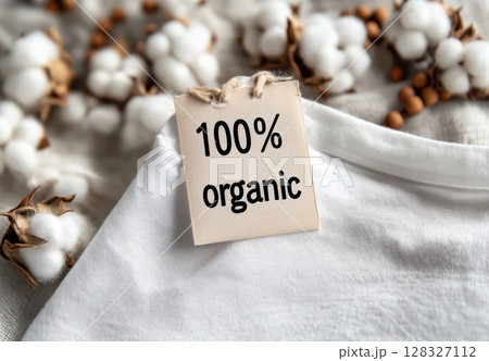 Soft organic cotton t-shirt features a 100% organic tag, surrounded by cotton and wooden beads, representing sustainable fashion choices. 128327112
