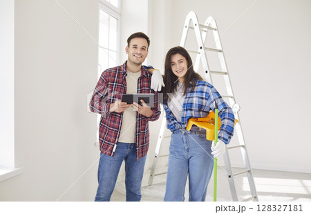 Happy couple after moving, planning future repair, using tablet in new home, young working friends 128327181